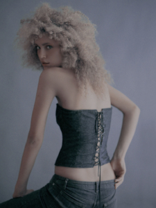 colour studio over the shoulder portrait of Joice wearing jeans and denim corset