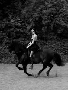 black and white location portrait of Karolyn riding a black Andalusian horse for Posh magazine Italy